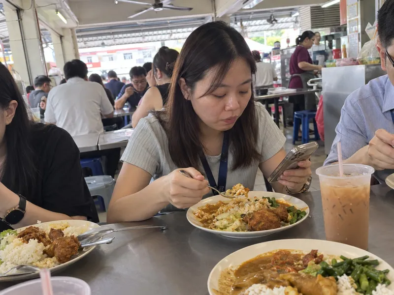 上班族午餐在咖啡店一边吃经济饭一边看手机