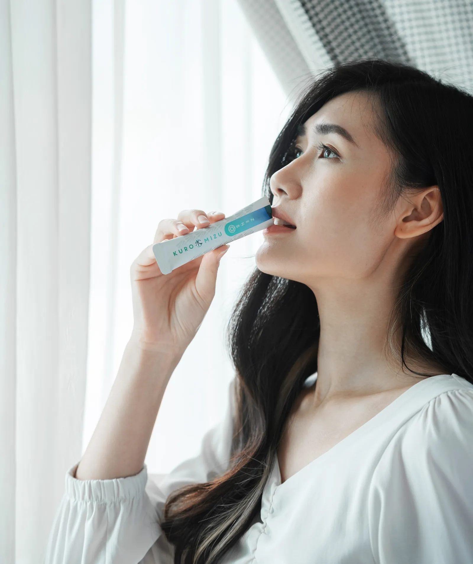 女生在窗边直接喝一包 Kuro Mizu